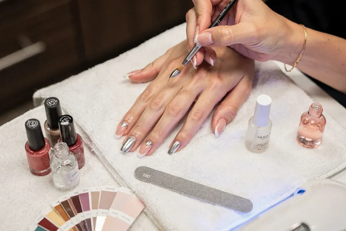 A nail technology student painting a client's nails
