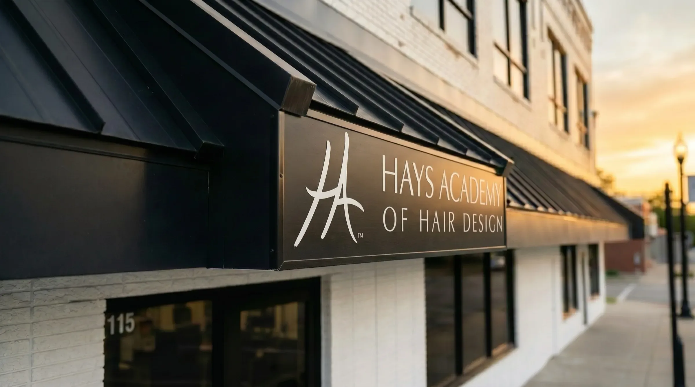 The Salina campus storefront at 115 South 5th Street at sunset, the Hays Academy sign under the awning