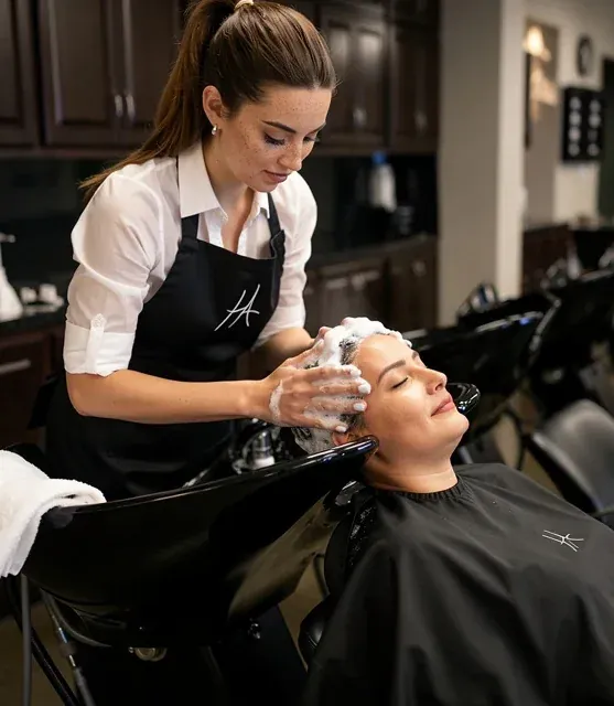 A student shampooing a client at the bowl
